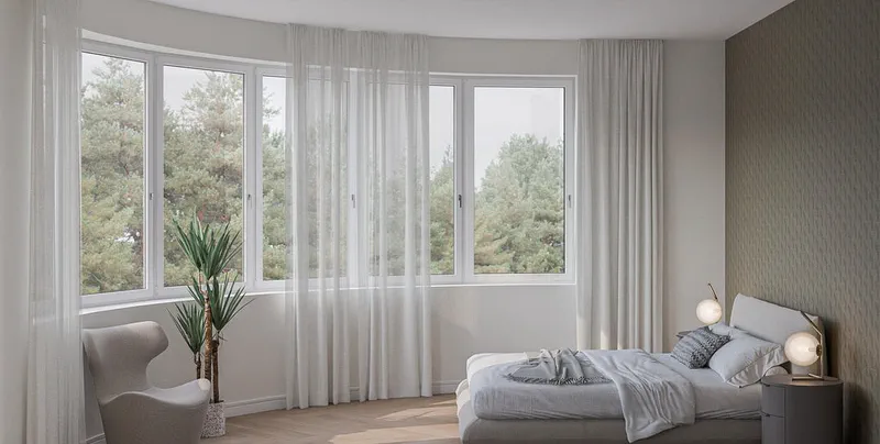 Schlafzimmer der Erdgeschosswohnung in der geschwungenen Gebäudeecke mit umlaufendem Fensterband.