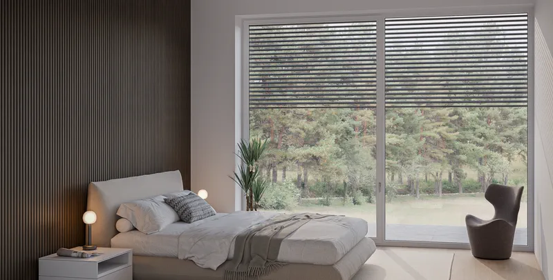 Schlafzimmer der Hanglagenwohnung mit großer Fensterfront zum Garten.